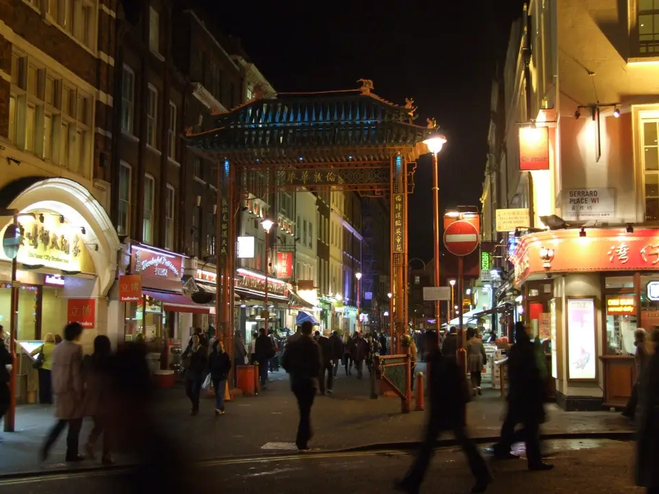Regent Street lit up at night, with a red bus and traffic passing the curved shopfronts