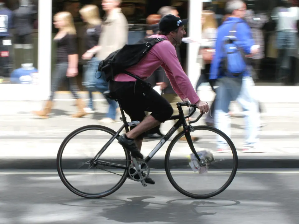 A bicycle courier riding past shoppers on Oxford Street