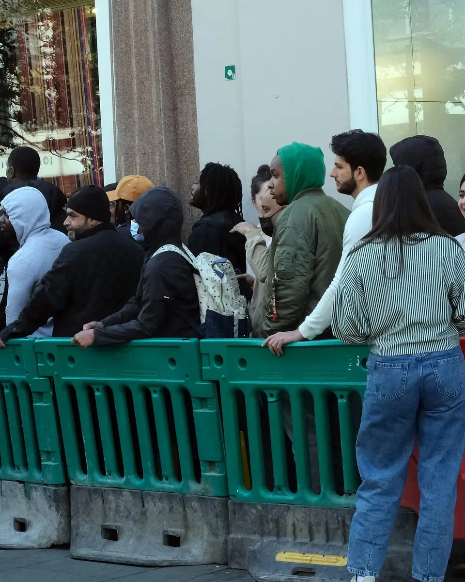 People queueing behind barriers outside a shop on Oxford Street, waiting for a new release
