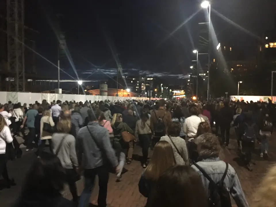 A large crowd walking along the road away from Wembley Stadium after a concert at night